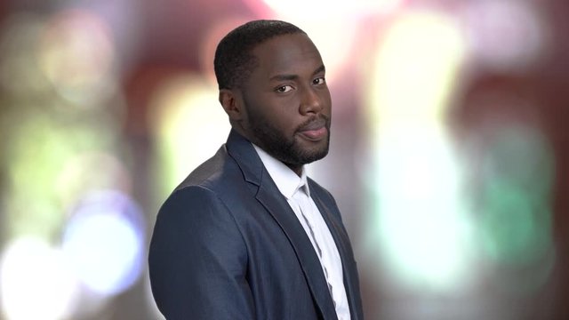 Sexy macho-man on blurred background. Flirty dark-skinned businessman.