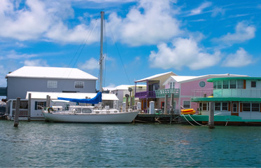 Fototapeta premium A sailboat moored near colorful houseboats at a marina near Key West.