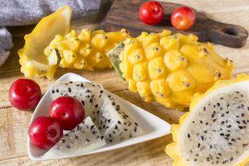 yellow pitahaya or dragon fruit and red plum on wooden background