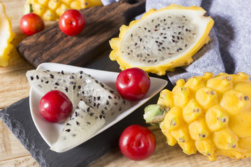 yellow pitahaya or dragon fruit and red plum on wooden background
