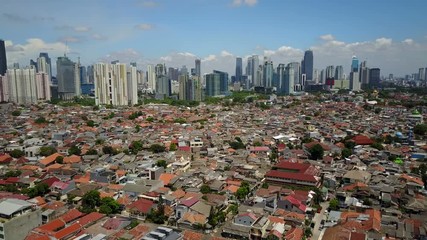 Establishing drone shot of low-rise buildings and modern office towers and Jakarta skyline, Indonesia