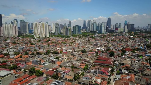 Establishing drone shot of low-rise buildings and modern office towers and Jakarta skyline, Indonesia