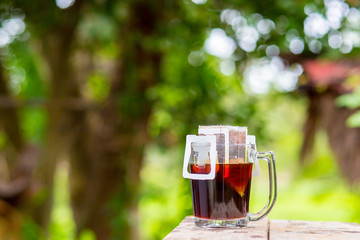 Hot coffee drip in the morning, sunlight shining in green.