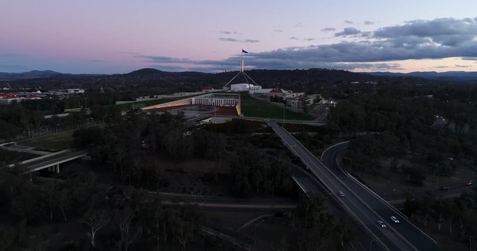 Public modern building of Australian federal parliament in Canberra capital city on Capitol hill with leading street motorway at sunset.
