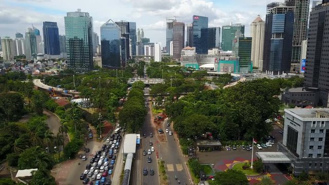 Aerial drone shot flying towards financial business district and flyover intersection under construction in Jakarta, Indonesia