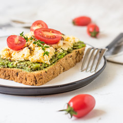 Scrambled eggs on whole wheat bread with avocado and cherry tomatoes