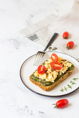 Scrambled eggs on whole wheat bread with avocado and cherry tomatoes
