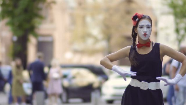 Beauitiful girl mime gesticulating hands at blurred street background