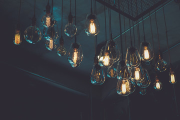 Beautiful vintage luxury light bulb hanging decor glowing in dark. Retro filter effect style.