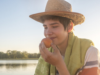close up young man smelling peach fruit ready to bite it on the beach copy space