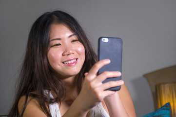 young sweet happy and pretty Asian Korean woman taking selfie picture with mobile phone for internet social media on mobile phone laughing at home