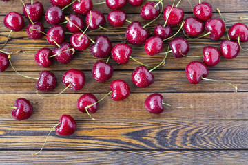Red ripe cherries, red cherries on wooden table, brown wooden background, top view