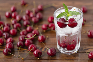 Summer iced drink -  cherry with ice and mint. On rustic wooden table