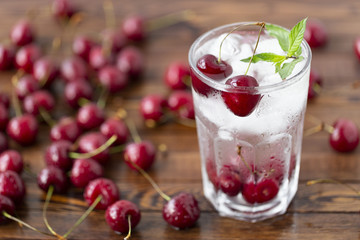 Summer iced drink -  cherry with ice and mint. On rustic wooden table