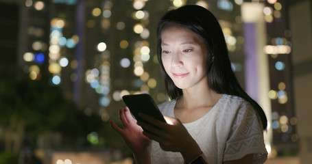 Young woman sending sms on cellphone at night