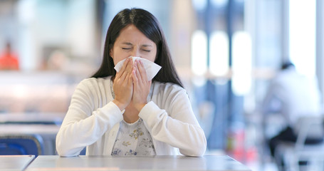 Woman sneezing inside shopping mall
