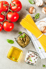 Food background, ingredients for cooking dinner.  Pasta spaghetti, vegetables, sauces and spices, grey stone background copy space top view