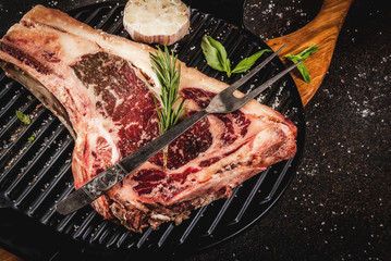 Raw beef marbled meat striplon rib eye steak with spices, grill pan, and herbs, dark background top view, copy space