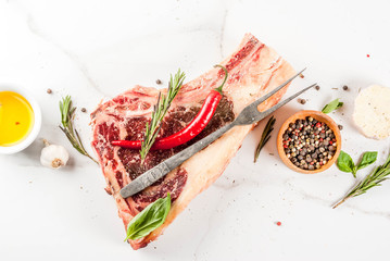 Raw beef marbled meat striplon rib eye steak with spices, herbs, white marble background top view, copy space