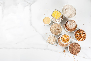 Selection various types cereal grains groats  in different bowl on white marble background, copy...