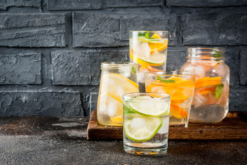 Summer healthy cocktails, set of various citrus infused waters, lemonades or mojitos, with lime lemon orange grapefruit, diet detox beverages, in different glasses dark background copy space