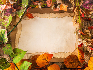 Naklejka na ściany i meble old paper among fake leaves on sackcloth