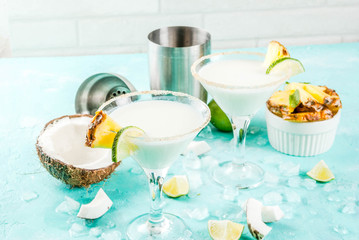 Tropical drink, Frozen Coconut Pineapple Margaritas with frozen pina colada, tequila, pineapple juice and lime,  light blue background, copy space - obrazy, fototapety, plakaty