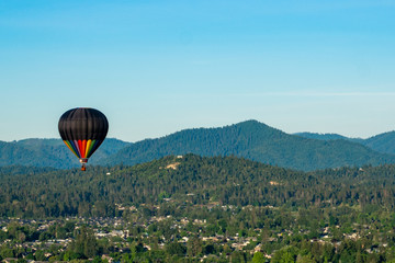 Naklejka premium Hot air balloon over wooded hillsides