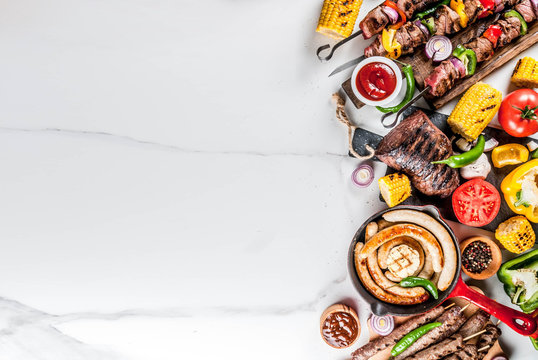 Assortment various barbecue food grill meat, bbq party fest - shish kebab, sausages, grilled meat fillet, fresh vegetables, sauces, spices, white marble background, above copy space
