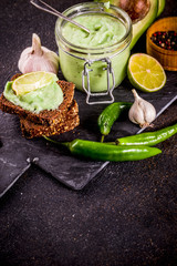 Mexican food, guacamole with rye toasts sandwiches on dark background, copy space