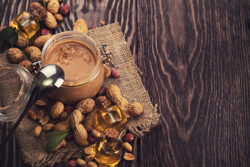 Natural peanut butter with oil in a glass jar and peanuts