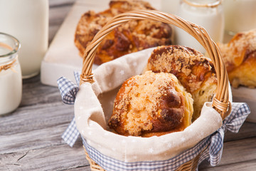 Bread buns in wicker basket and jars with milk 