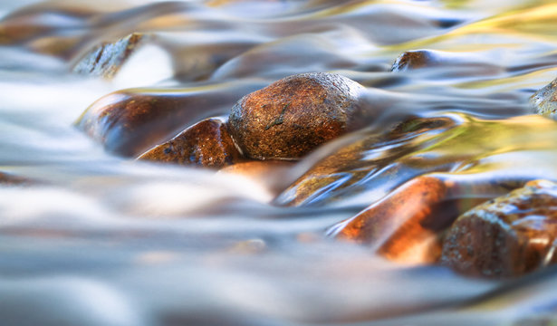 Long exposure of a small stream gently flowing over rounded rocks in the Cathedral Range State Park, Victoria, Australia.