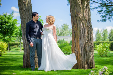 Romantic wedding moment, couple of newlyweds smiling portrait, bride and groom hug while on a walk in the park. Loving wedding couple outdoor. Bride and groom 