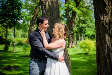 Fototapeta premium Romantic wedding moment, couple of newlyweds smiling portrait, bride and groom hug while on a walk in the park. Loving wedding couple outdoor. Bride and groom 