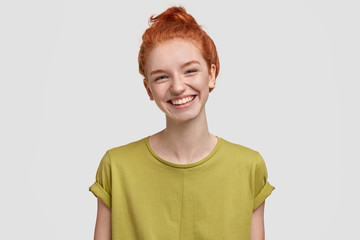Cheerful freckled woman with gentle smile, feels confident and satisfied, happy to finish working on project, isolated over white background. Redhead young female models indoor, has white teeth