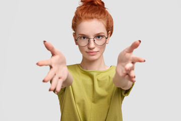 Cropped view of adorable serious freckled ginger female stretches hands and looks directly at camera, gives hug to you, isolated over white background. I want to embrace my best friend. Come here!