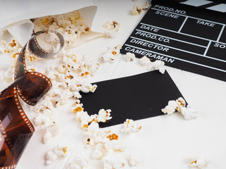 the film in the spiral, near the popcorn, Clapperboard copy space for text, fashion highlights in the photo, concept, film industry, film, abstract composition of movie, on a white background