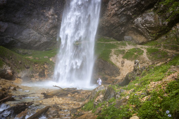 European man with beard is doing waterfall-meditation while standing under big waterfall in austria, wildensteiner waterfall
