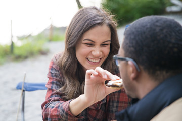 Obraz premium Happy couple feeding each other s'mores at camp site