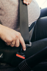 Anonymous pregnant woman wear safety belt in the car
