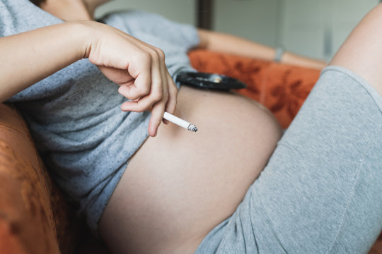 Pregnant woman smokes a cigarette