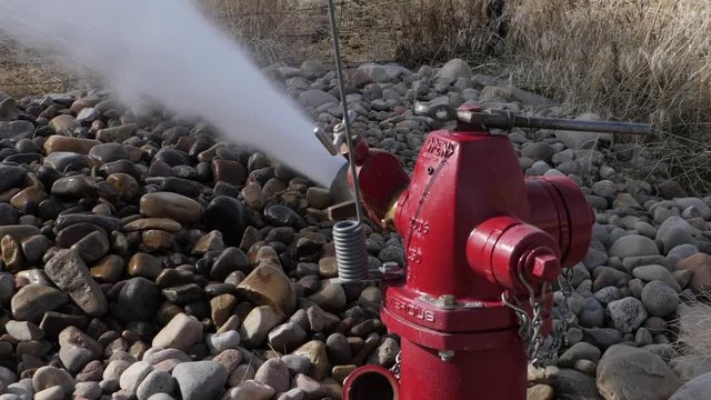 Slow motion of workers trying to fix a broken fire hydrant at the end of street