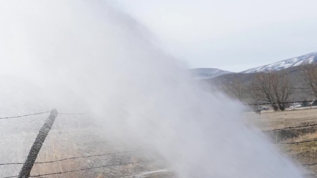 Slow motion people trying to fix a broken fire hydrant at the end of a street