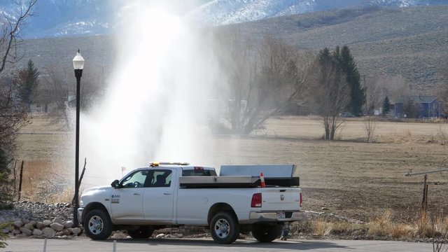 Slow motion workers fixing a broken fire hydrant at the end of a street
