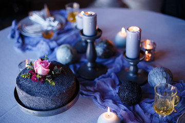Dinner table with black plate with black candles on candlesticks. Luxurious wedding decor. Poppy cake in the foreground