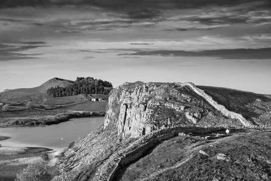 Beautiful black and white landscape image of Hadrian's Wall in Northumberland at sunset with fantastic late Spring light