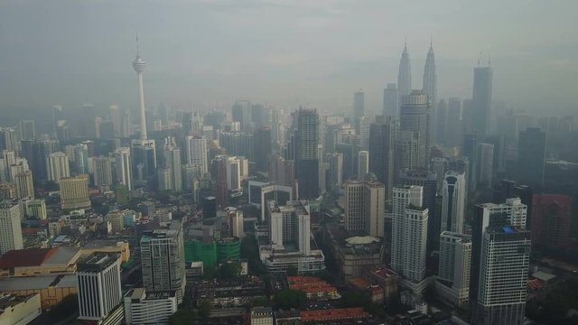 Panoramic aerial drone shot of famous Petronas twin towers and other skyscrapers in Kuala Lumpur, Malaysia's capital city
