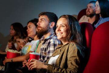 Group of friends sitting in movie theater with popcorn and drinks