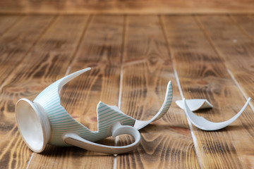 A broken vintage porcelain cup on a wooden table (top view)